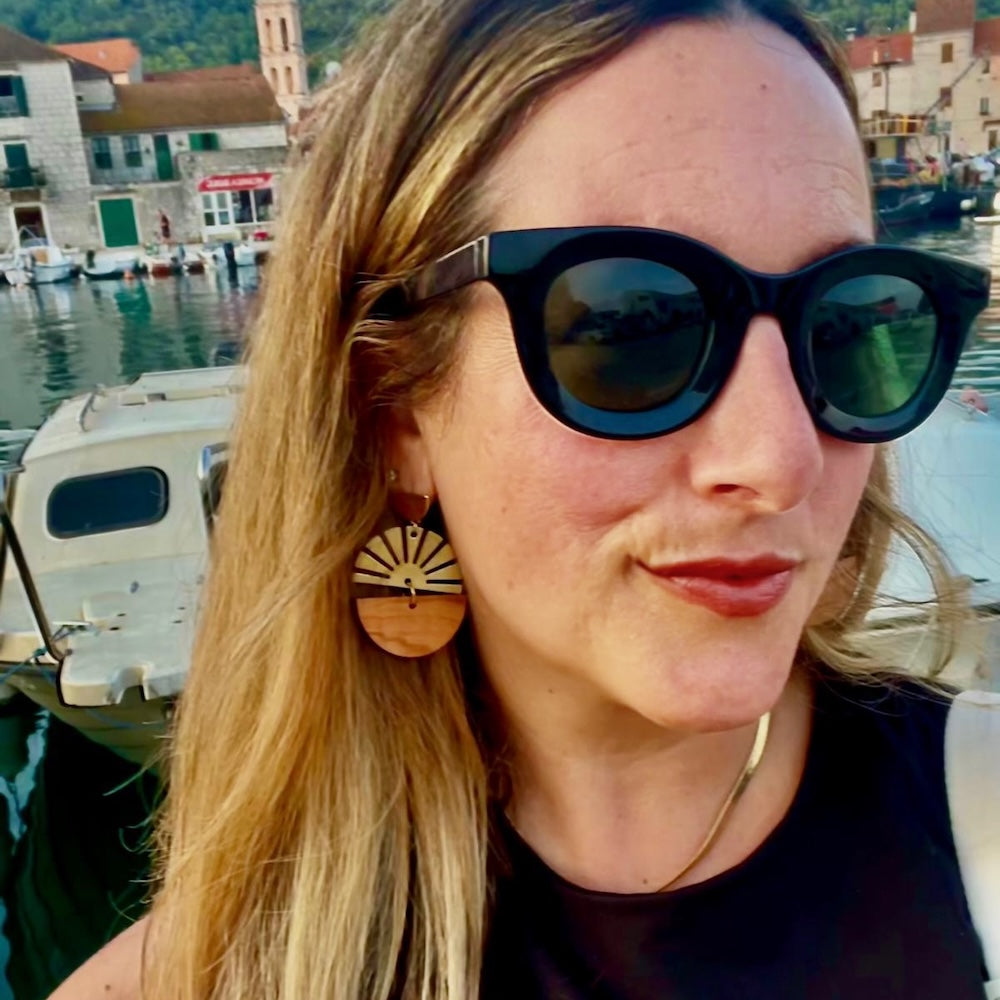 Woman by the Adriatic Sea wearing Madera Design Studio Brass Earrings-Croatian olive wood and starburst brass charm.