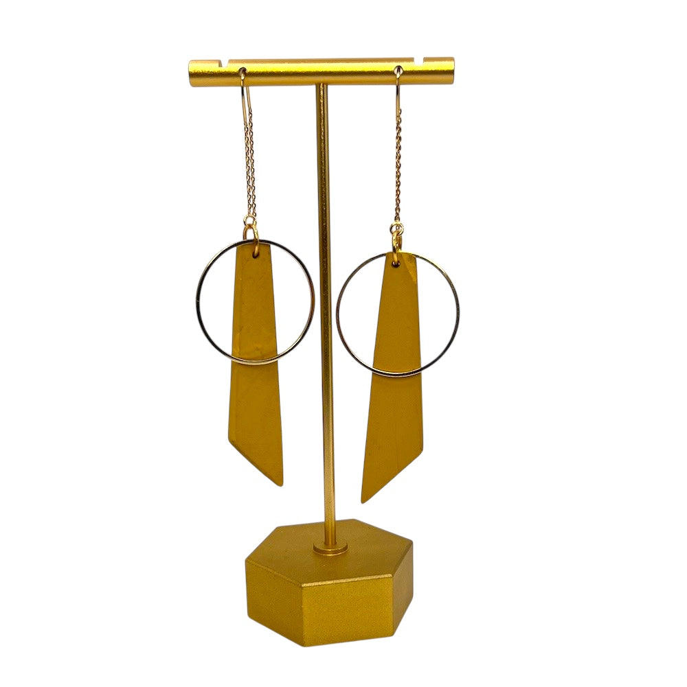 Gold earring stand with two gold earrings on a white background