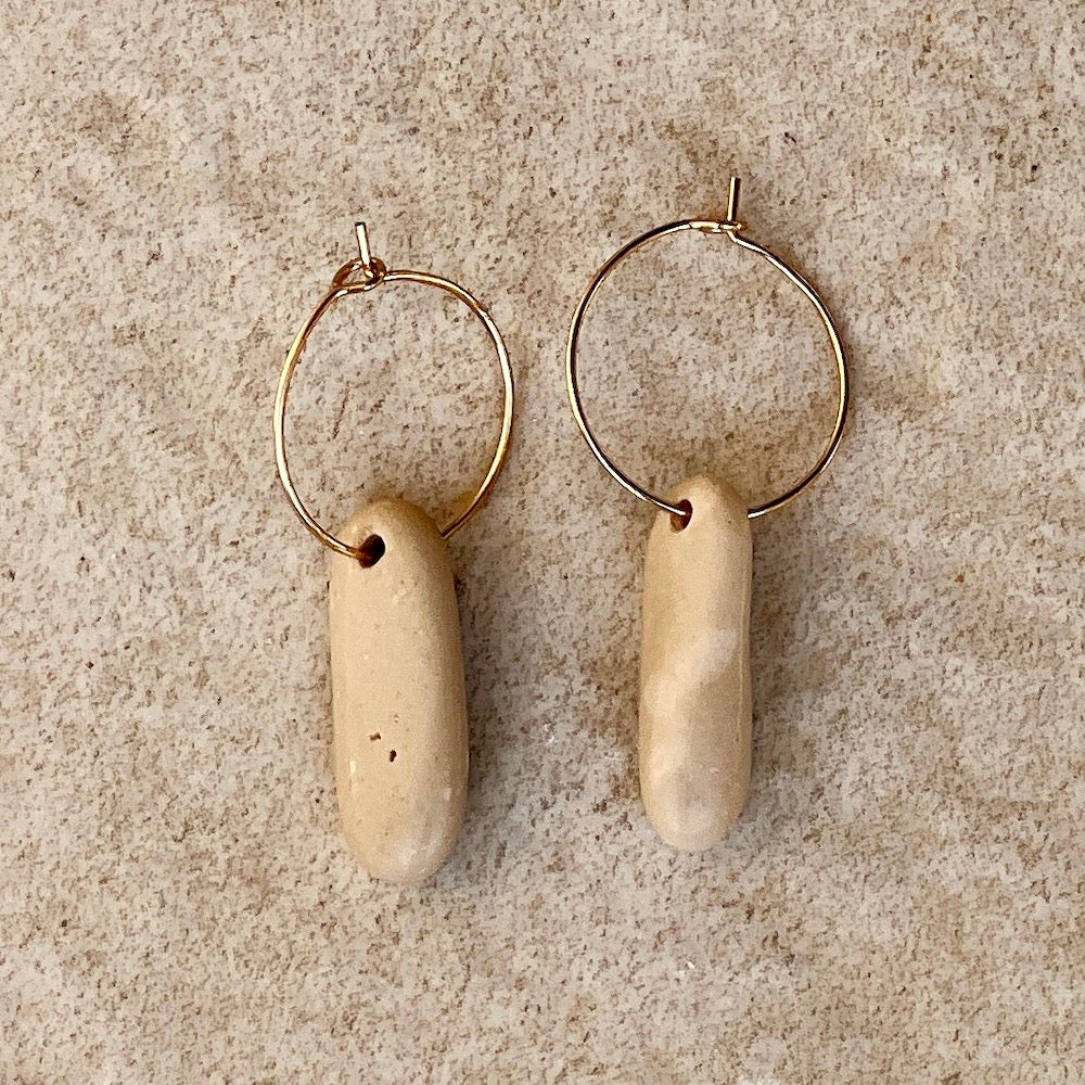 oval pebble stone earring on stone background