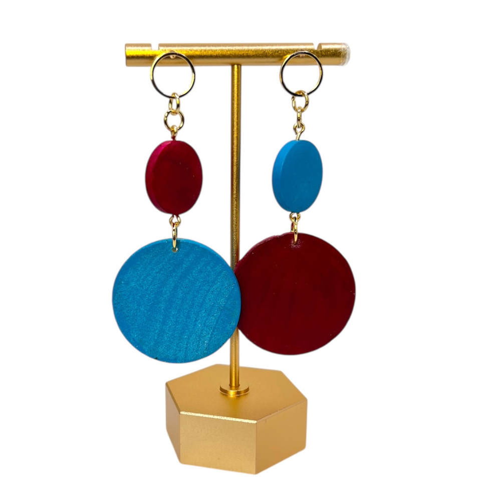 Colorful earrings on a gold stand against a white background