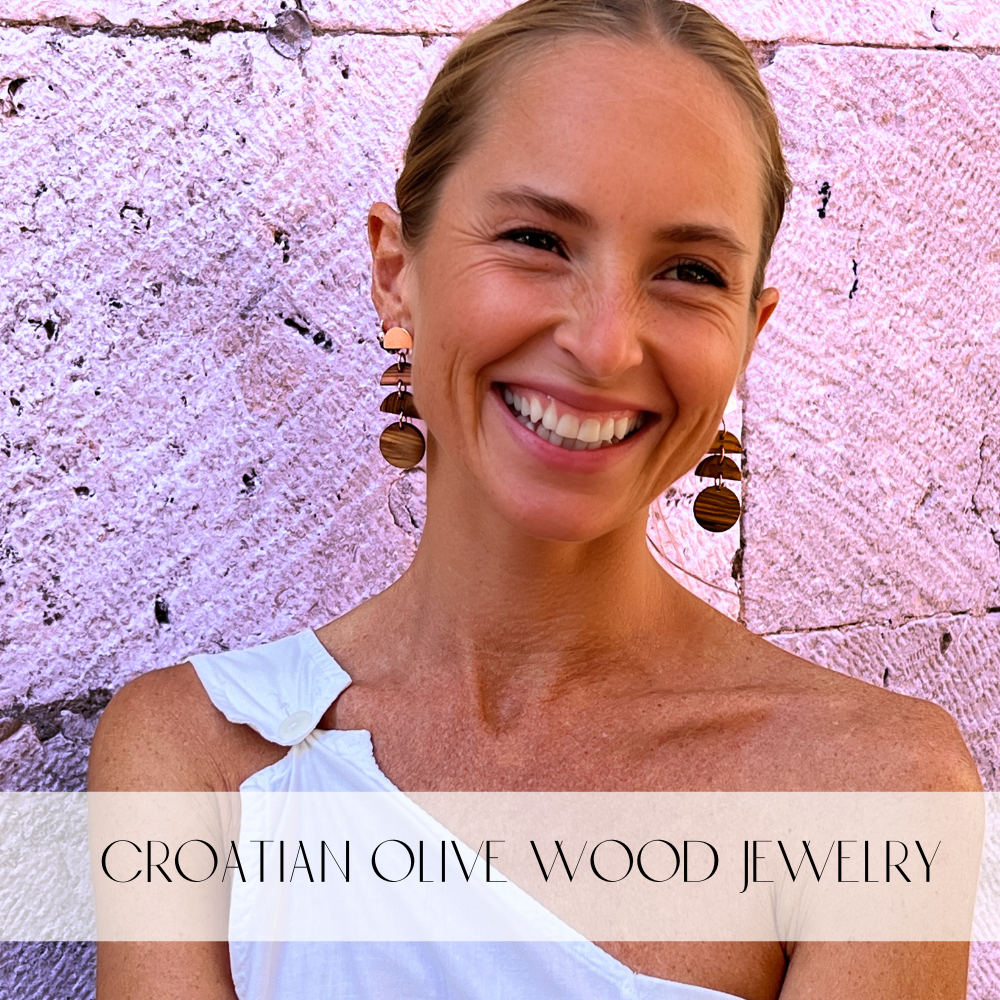 Olive Wood Moon Phase earrings on model in white shirt by stone wall