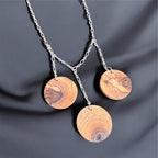 Three olive wood disks hang from a sterling silver plated chain on a black silk background