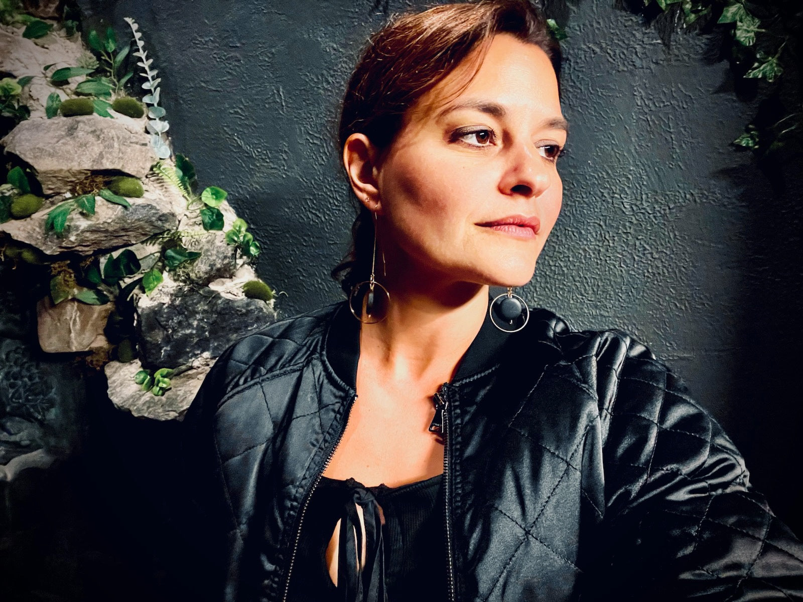 User generated content woman wearing black threader earrings on black background in black jacket