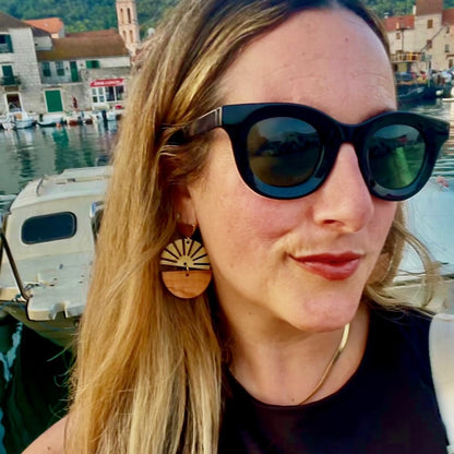Woman by the Adriatic Sea wearing Madera Design Studio Brass Earrings-Croatian olive wood and starburst brass charm. 