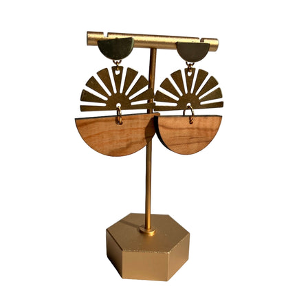 Pair of gold and wooden earrings on a matching stand against a white background