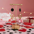 Black bead and brass marquise earrings on a gold stand.