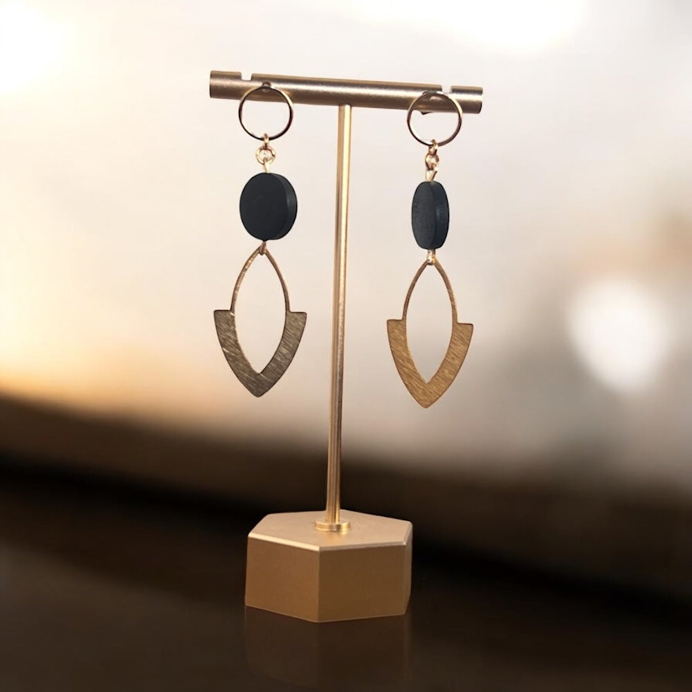 Pair of earrings on a gold stand with a soft background