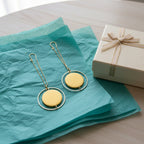 Gold painted threader earrings haning on a gold stand.
