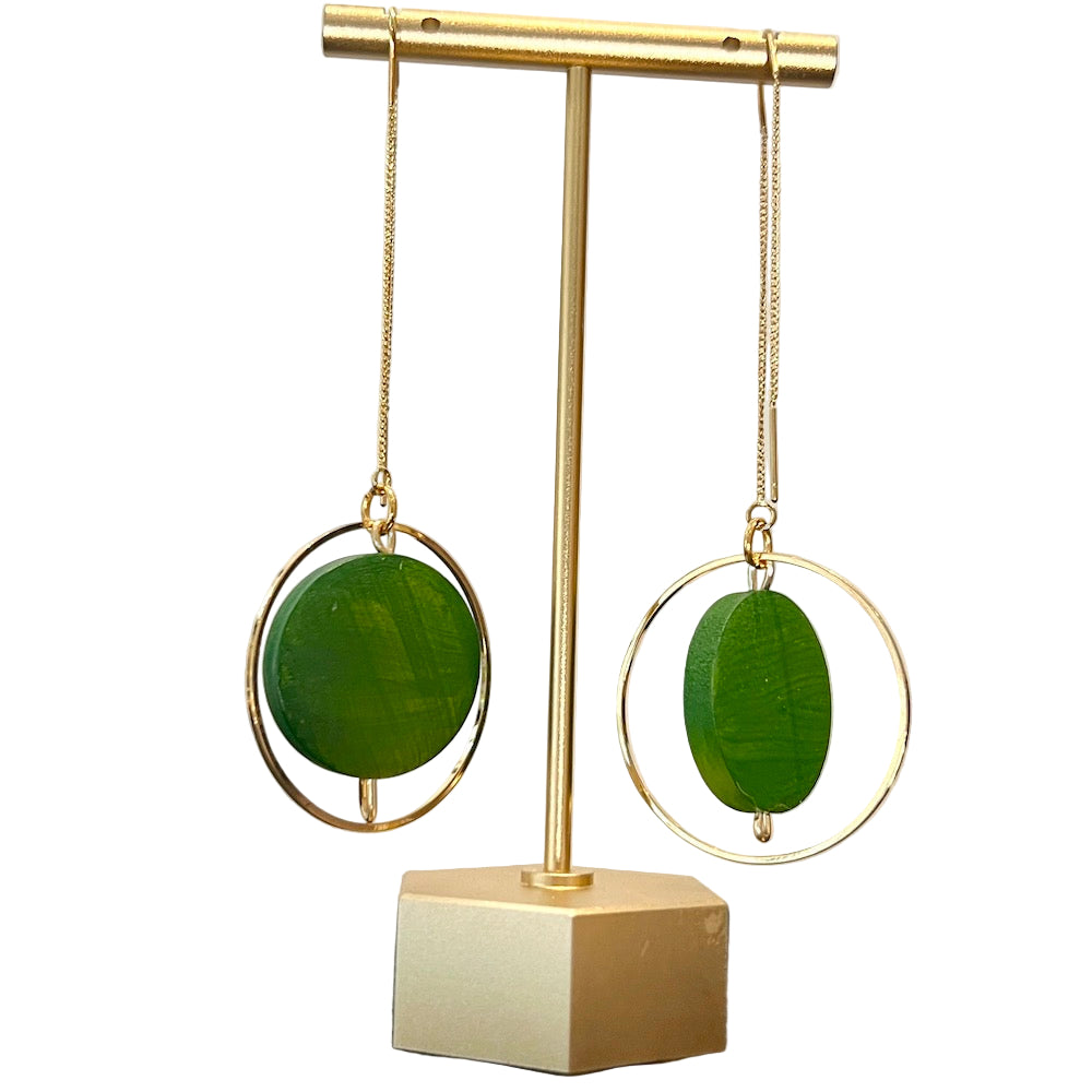 Green painted earrings on a gold stand with a neutral background