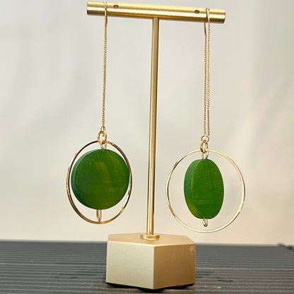 Green painted earrings on a gold stand with a neutral background