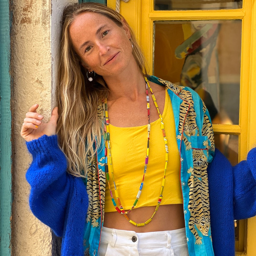 Justina Mastna creator at Jusinart - in yellow and blue in front of yellow window