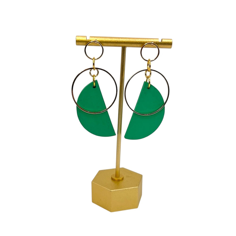 Green earrings on a gold earring stand against a white background
