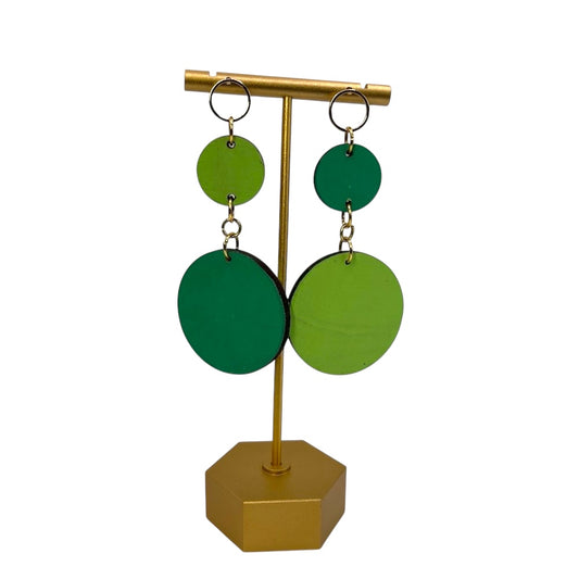 Green circular earrings on a gold stand against a white background