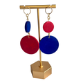 Colorful earrings on a gold stand against a white background