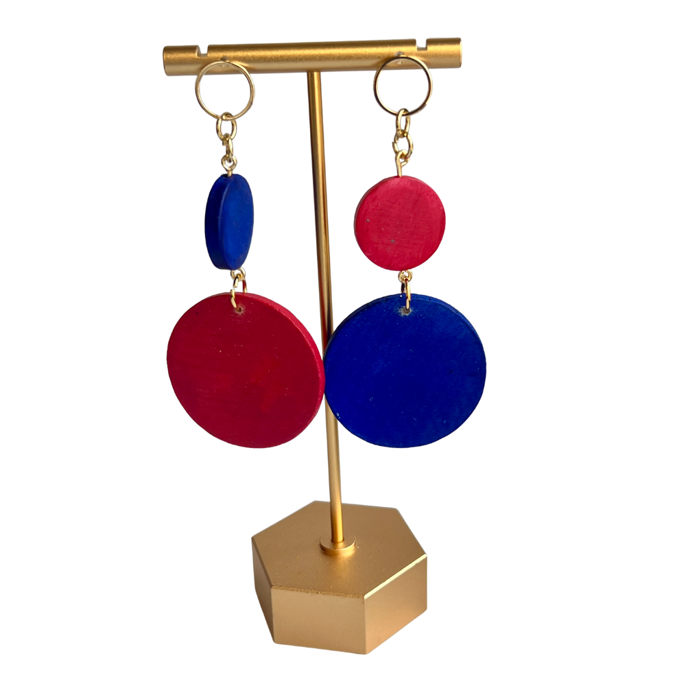 Colorful earrings on a gold stand against a white background