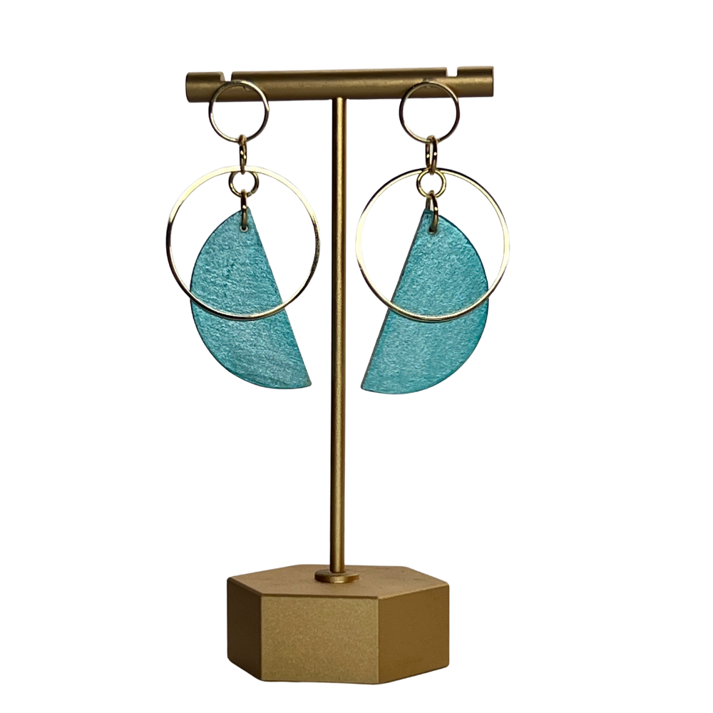 Teal earrings on a gold earring stand against a white background