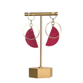 Gold earring stand with pink earrings on a white background