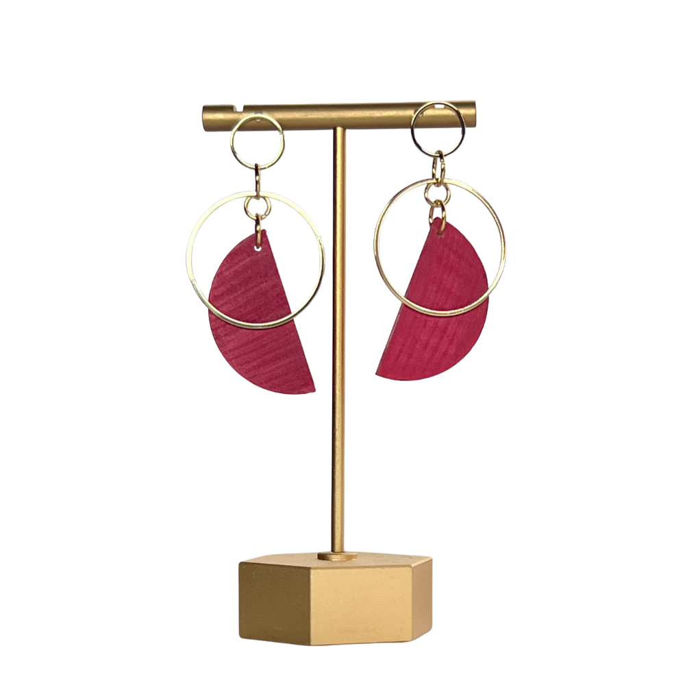 Gold earring stand with pink earrings on a white background