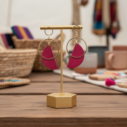 Gold earring stand with pink earrings on a white background