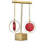 Burgundy earrings hanging on a stand.