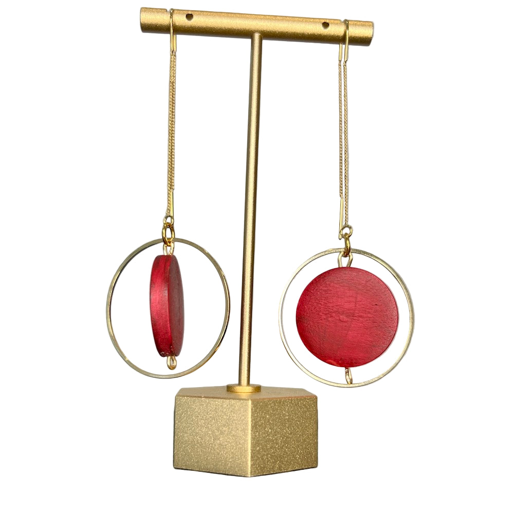 Burgundy earrings hanging on a stand.