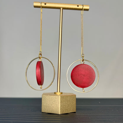 Burgundy earrings hanging on a stand.