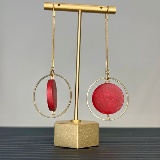 Burgundy earrings hanging on a stand.
