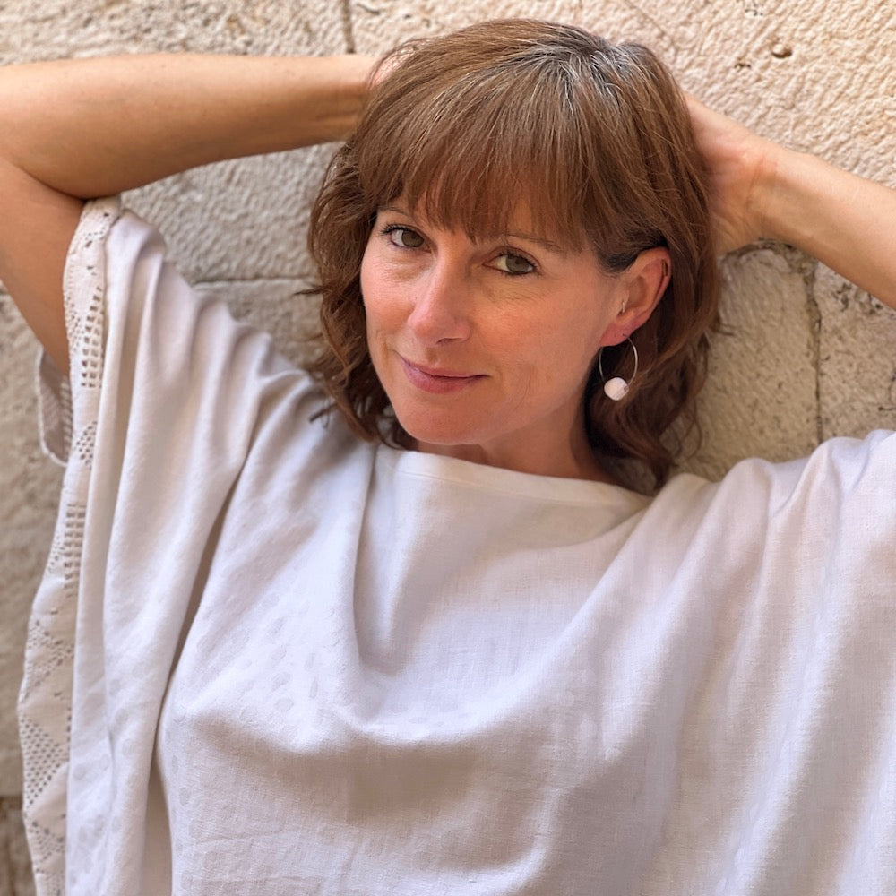 Stacey Shevlin wearing single white bead recycled paper earrings