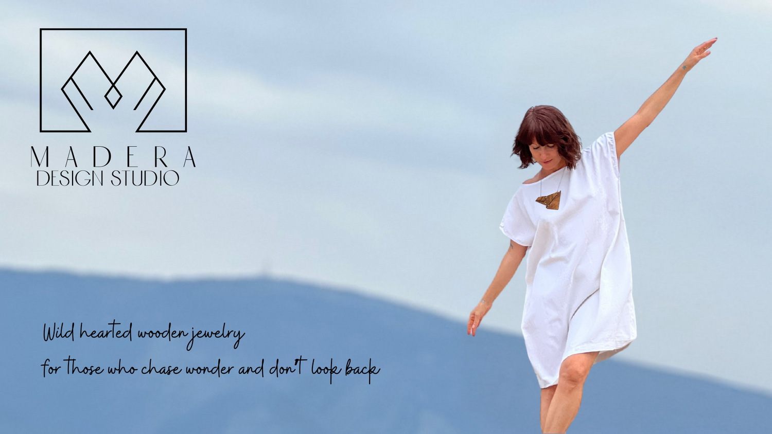 Woman in a white dress standing on a beach with 'Madera Design Studio' branding.