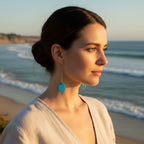 Hand painted caribbean blue hexagon wood bead hangs from a rigid gold threader earring - hanging from an earring display. Handcrafted by Madera Design Studio 