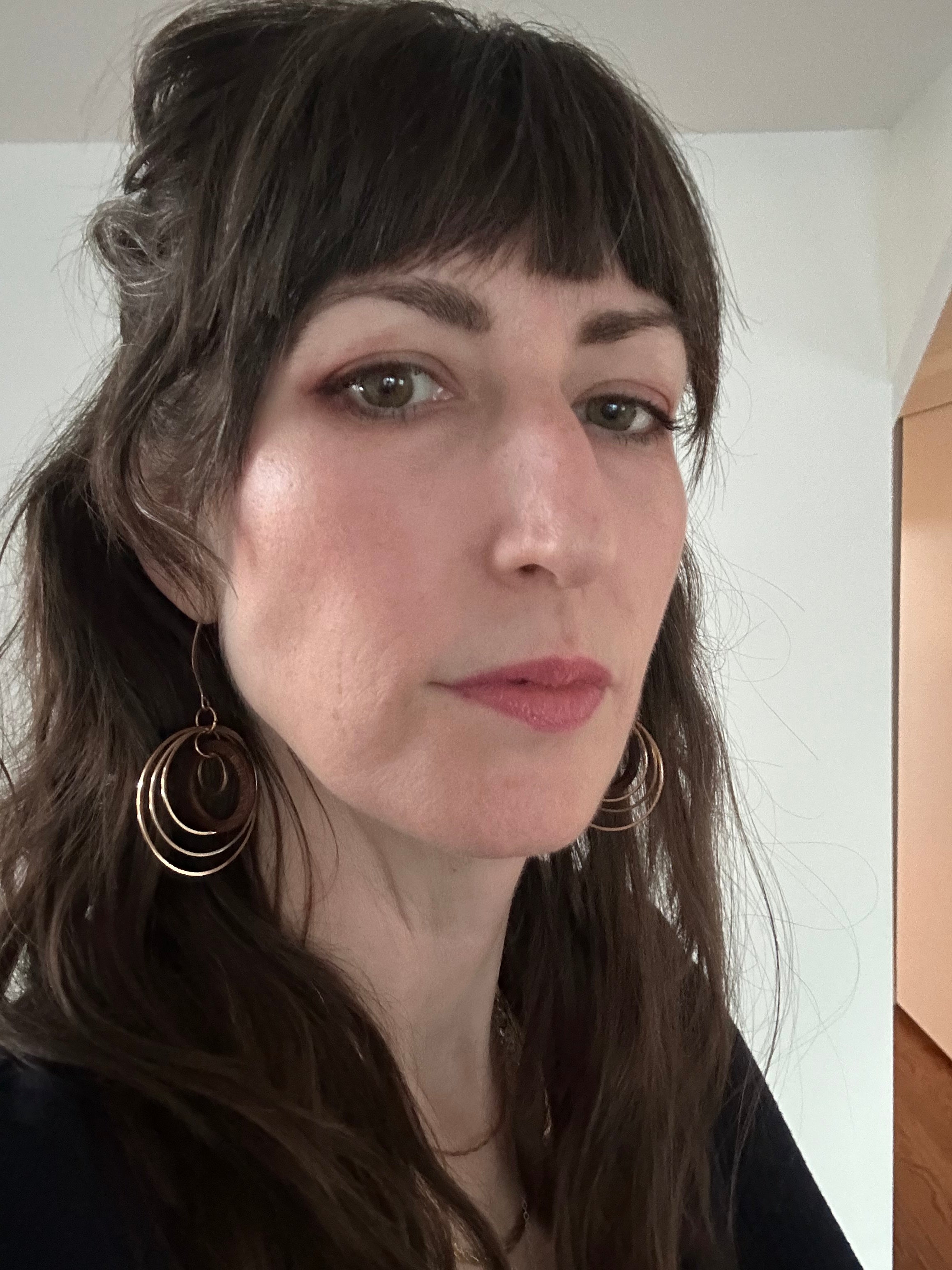 user generated content, woman customer wearing circles earrings, hair half up black shirt