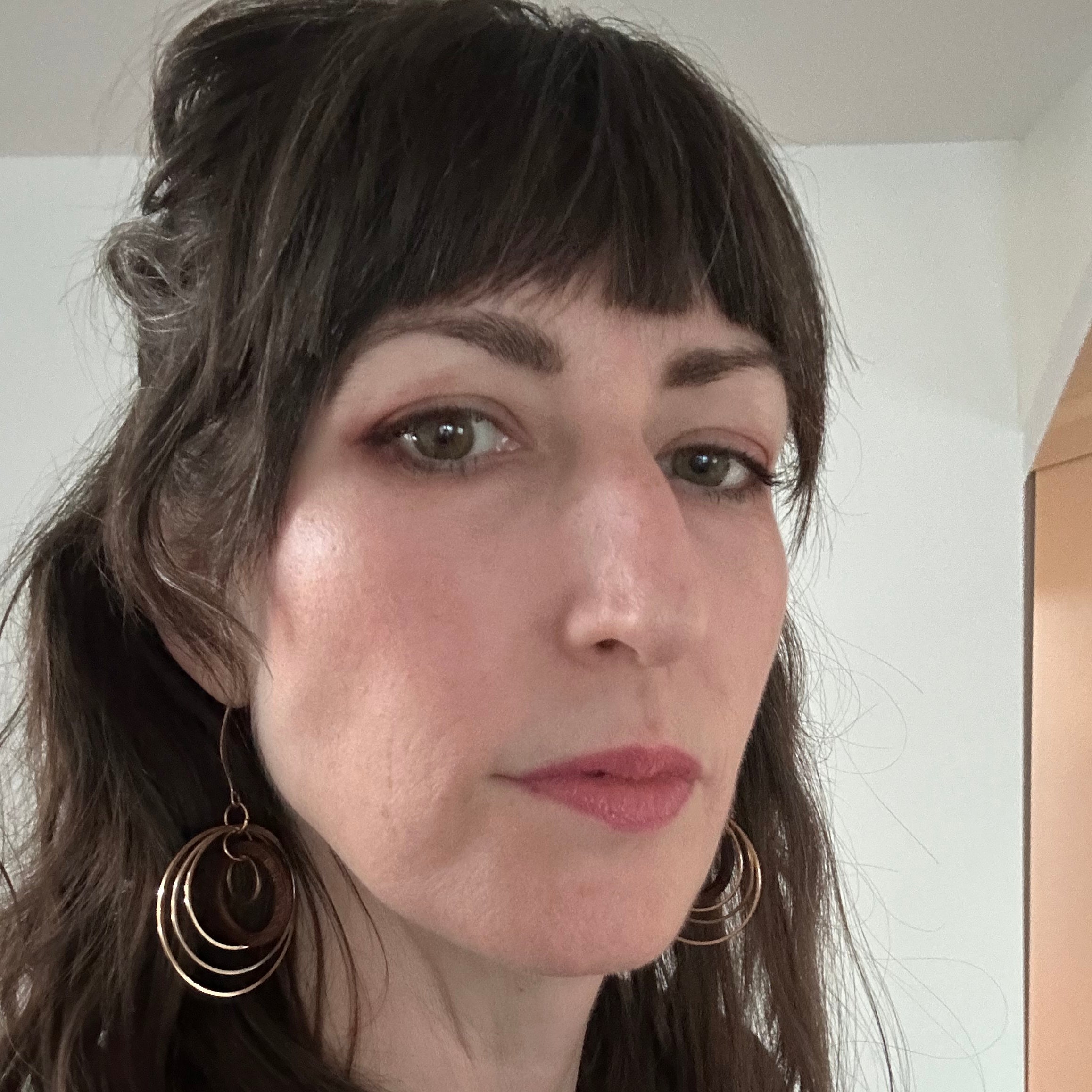 user generated content, woman customer wearing circles earrings, hair half up black shirt