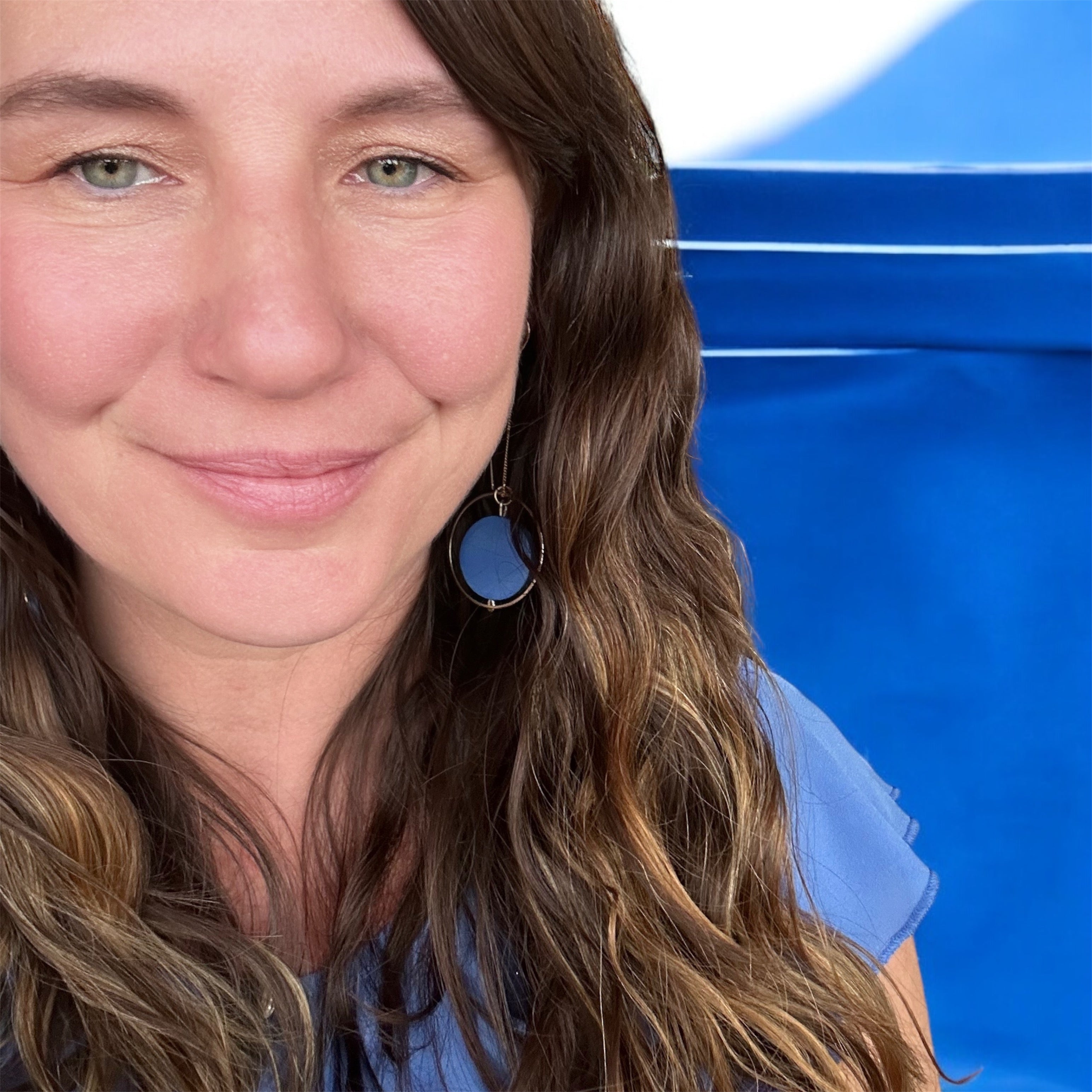 user generated content, woman customer wearing cobalt threader earrings on blue background