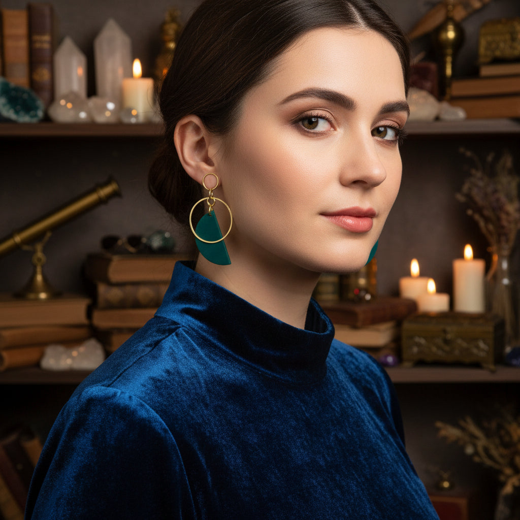Gold earring stand with green earrings on a white background