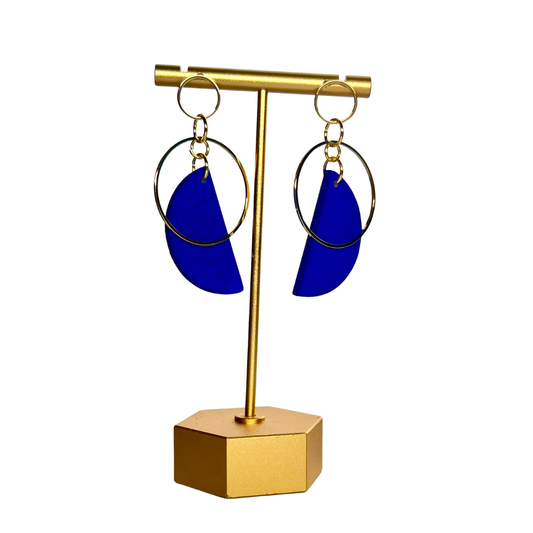 Gold earring stand with blue earrings on a white background