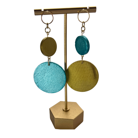 Pair of earrings with blue and gold circular pendants on a gold stand.