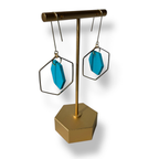Gold earring stand with blue earrings on a white background