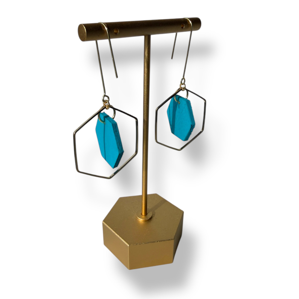 Gold earring stand with blue earrings on a white background