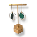 Gold earring stand with green earrings on a white background