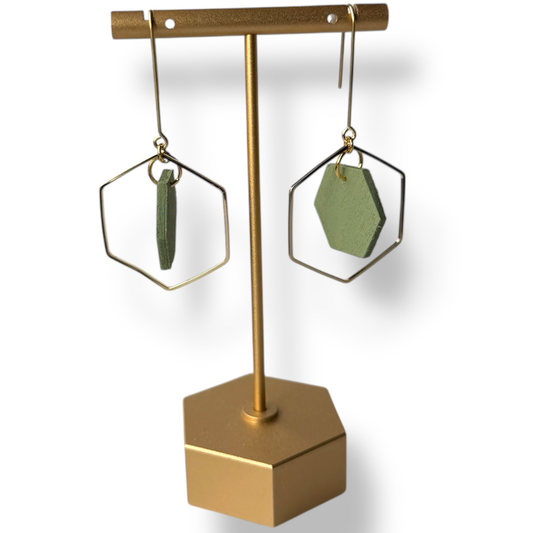 Gold hexagonal earring stand with green hand painted earrings on a white background