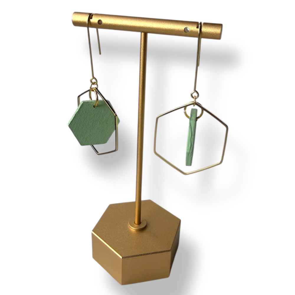 Gold earring stand with green earrings on a white background