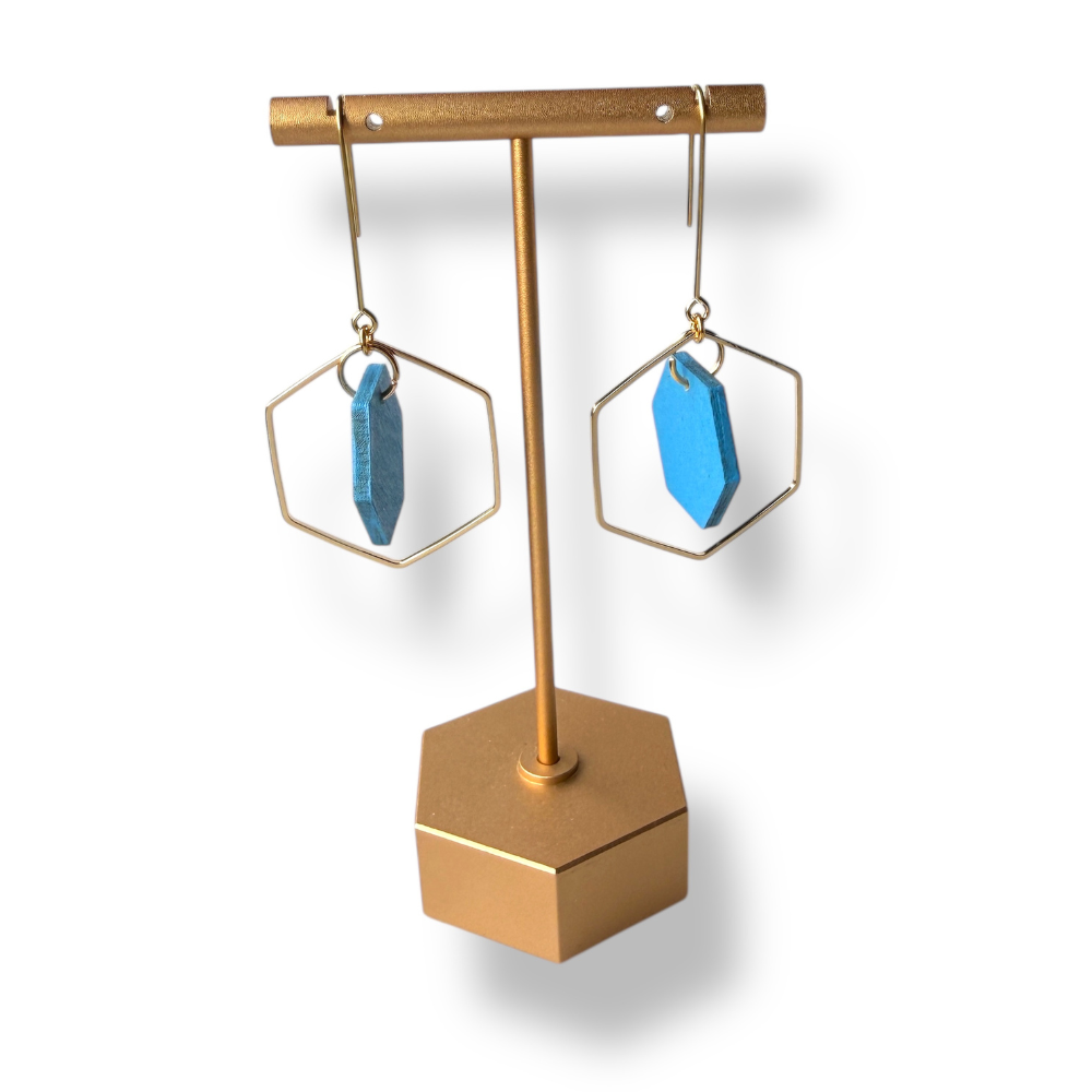 Gold earring stand with blue earrings on a white background