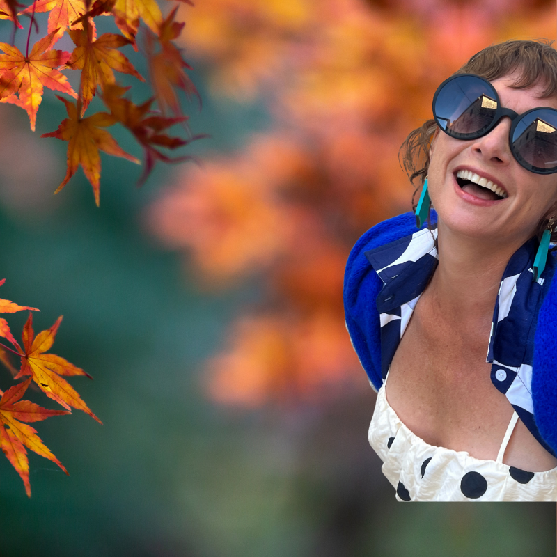 Woman wearing sunglasses  and Mad Era Earrings with a colorful autumn leaf background