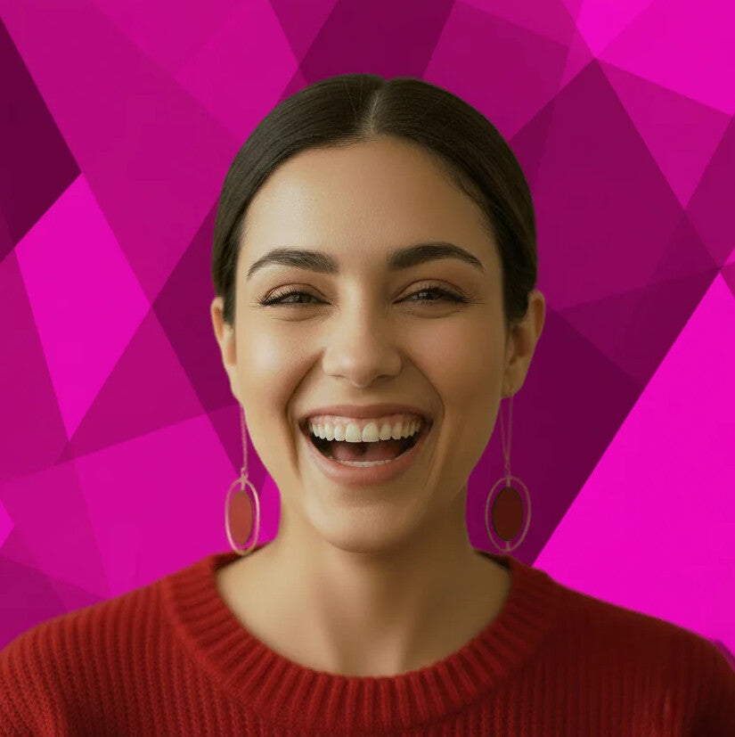 Woman wearing a red sweater and hoop earrings against a pink geometric patterned background