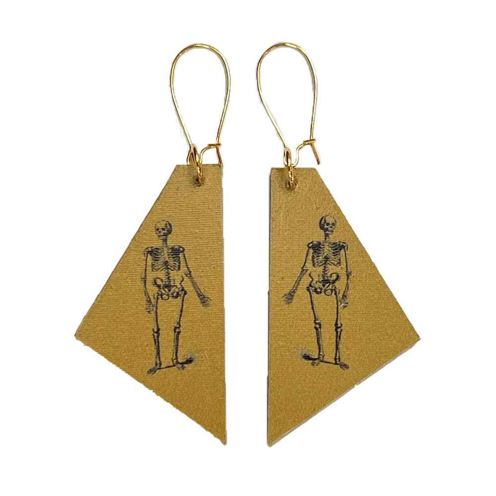 Madera design studio skeleton earrings on mustard yellow background