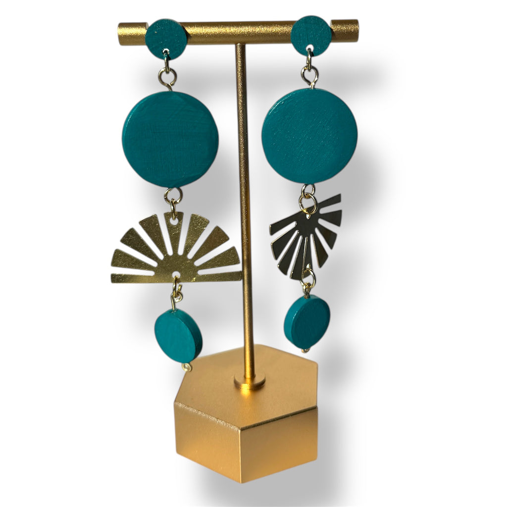 Teal earrings with gold and silver accents on a gold stand against a white background