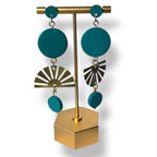 Teal earrings with gold and silver accents on a gold stand against a white background